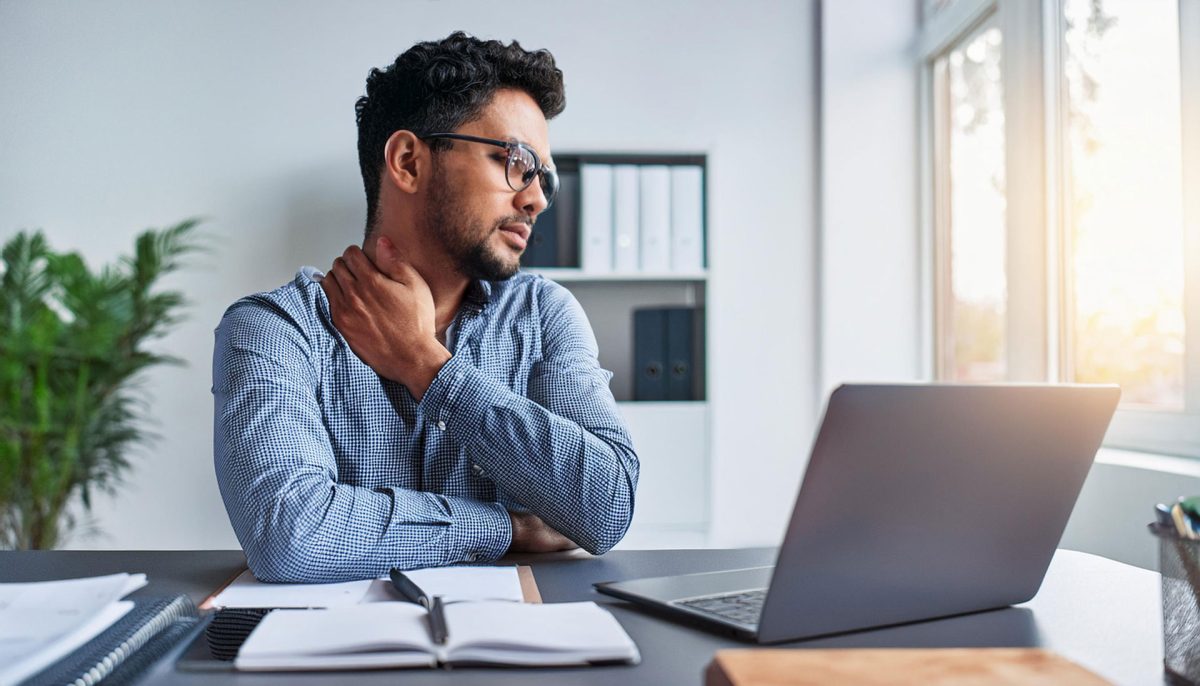 man-sitting-in-office-at-desk-with-a-strain-in-his-neck-4255-1200x686.jpg